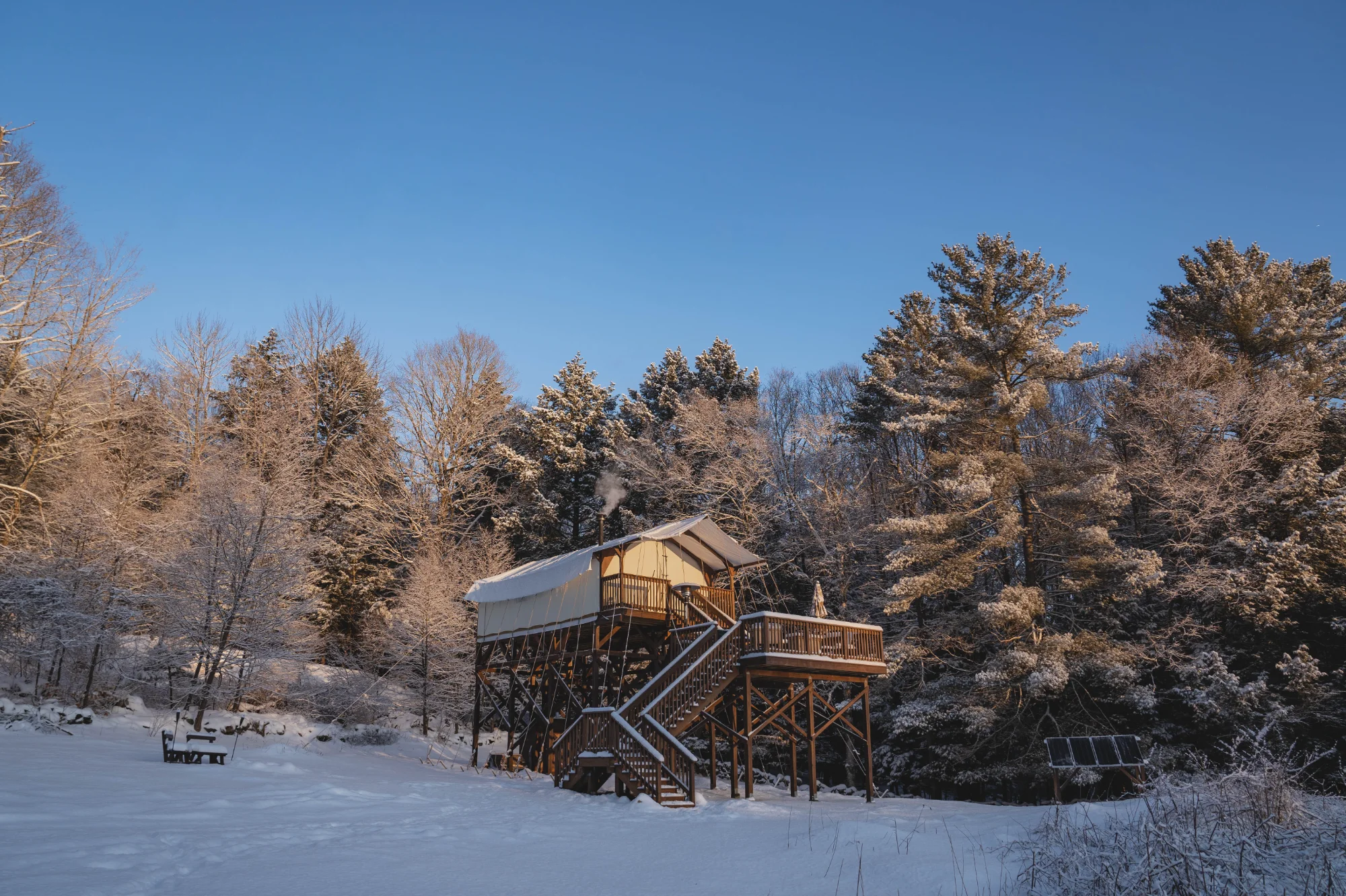Winter wonderland with tent and smoke rising